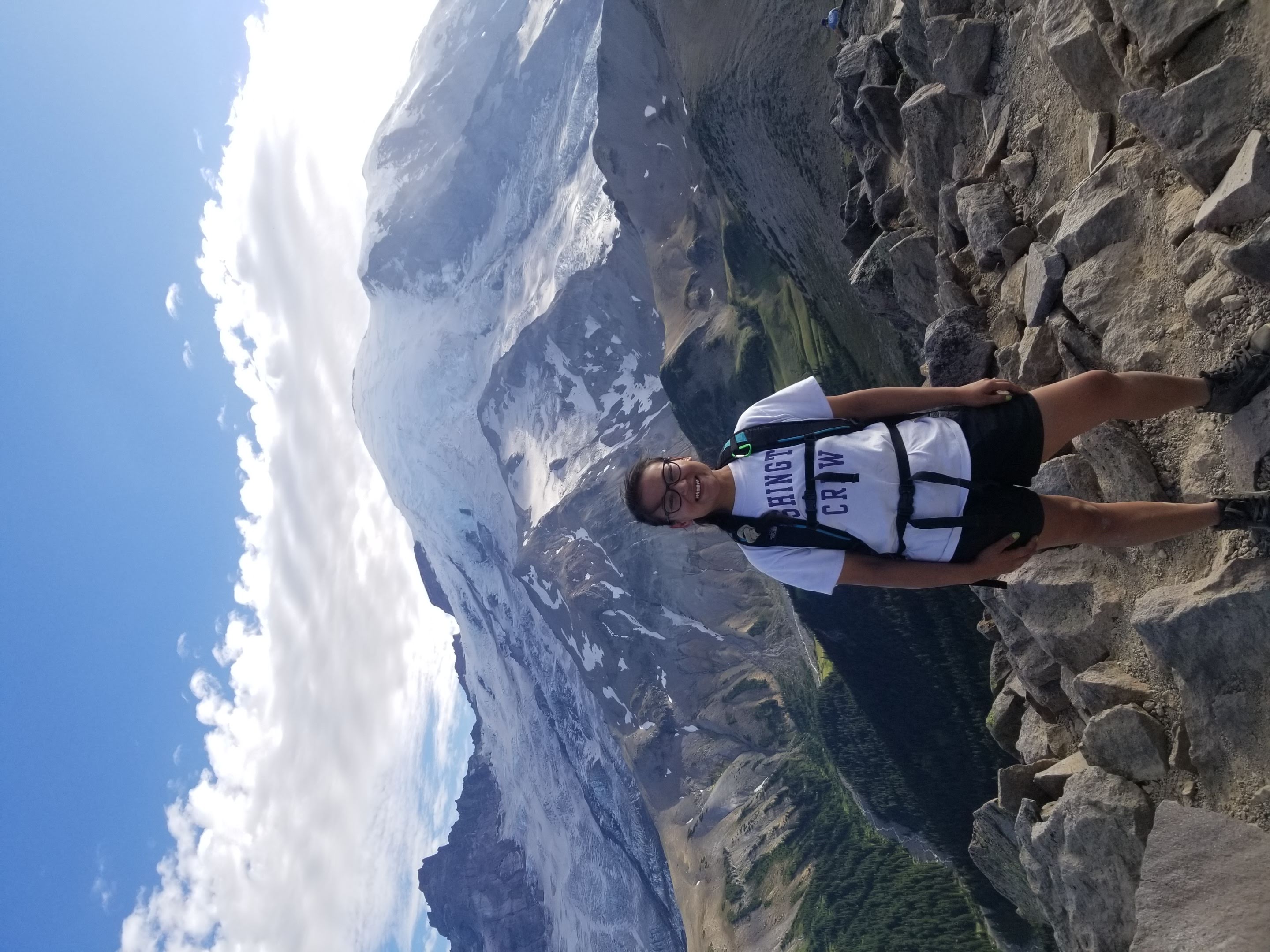 mount rainier in the back with a girl in front of it, on a ridge